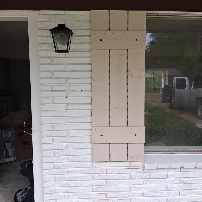 Window shutters installation on brick exterior with light fixture
