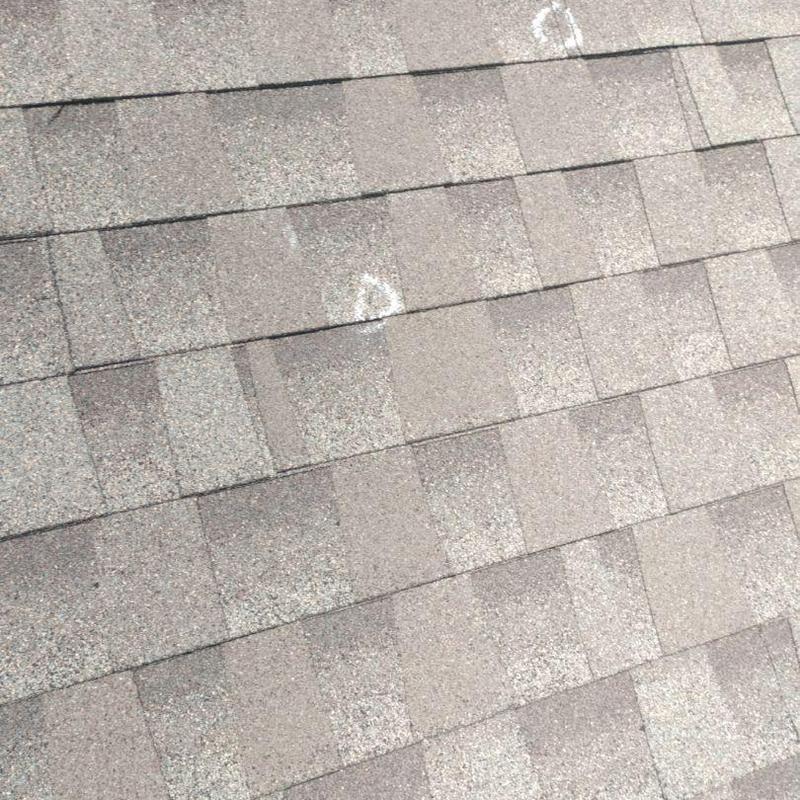 Asphalt shingle roof with hail damage marked for inspection