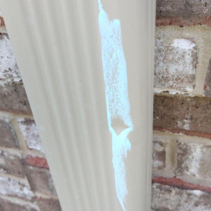 Damaged beige metal gutter with hail dent and scrape