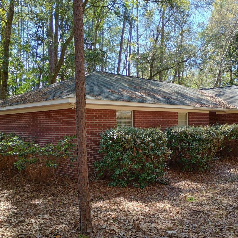Asphalt shingle roof on brick house with surrounding trees Asphalt shingle roof on brick house with surrounding trees