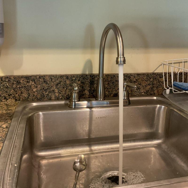 Kitchen faucet with water running over sink basin