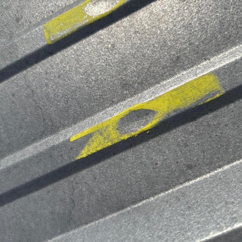 Metal roofing panel with hail damage marked in yellow paint