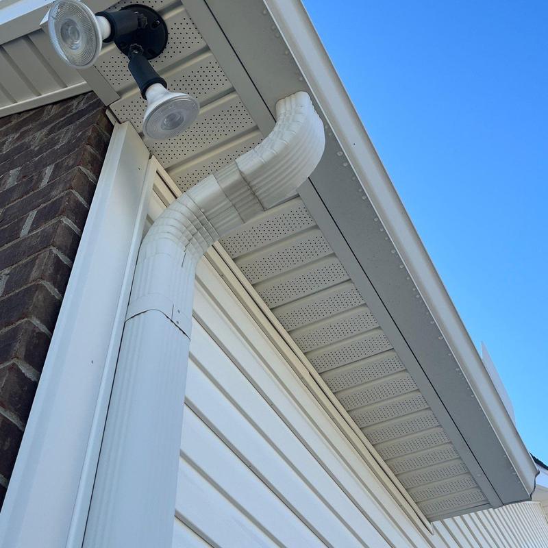 White vinyl downspout with elbow joint by house exterior