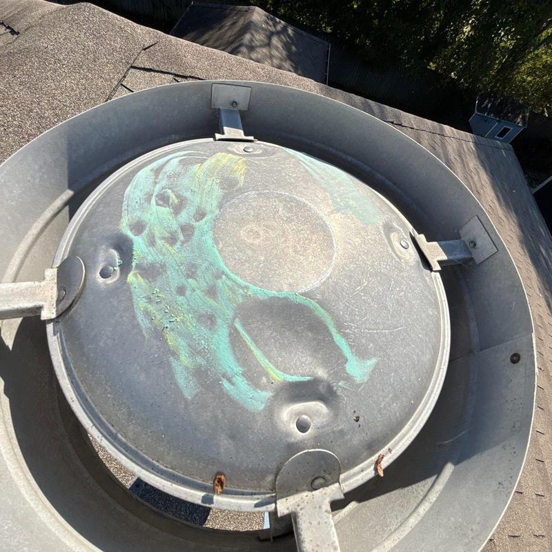 Roof ventilation cap with hail damage and discoloration
