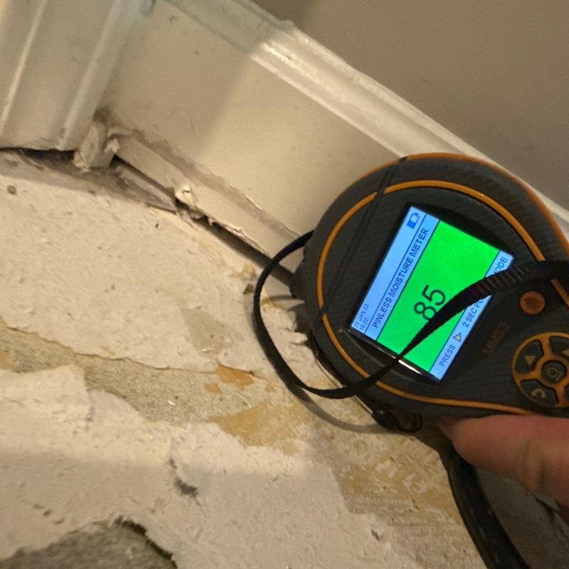 Drywall moisture meter reading near baseboard trim