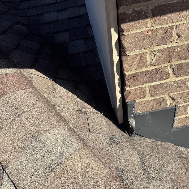 Roof flashing and shingles near brick chimney corner