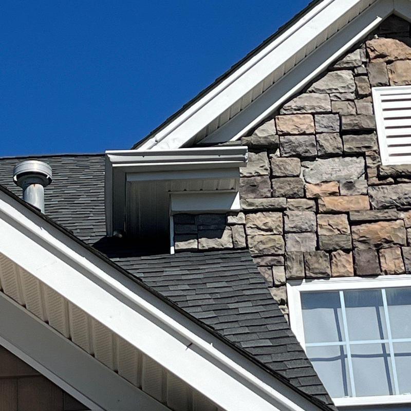 Asphalt shingle roof with stone siding and vent detail