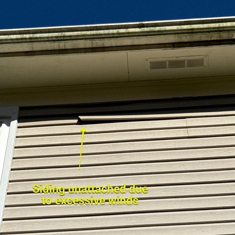Vinyl siding panel unattached from wall due to wind damage