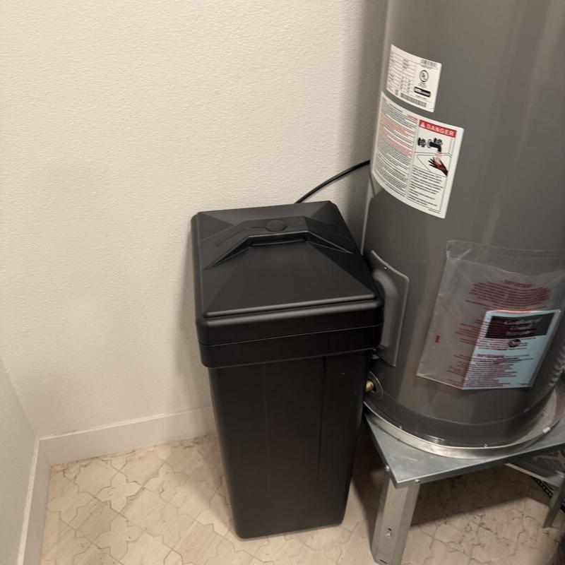 Water softener unit next to water heater in utility room Water softener unit next to water heater in utility room