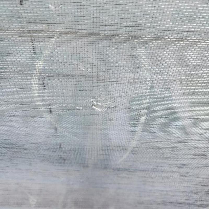 Window screen with hail damage and puncture holes