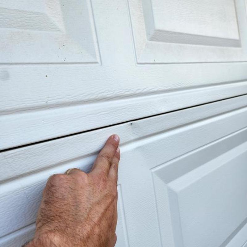 Garage door cosmetic hail damage close-up with hand