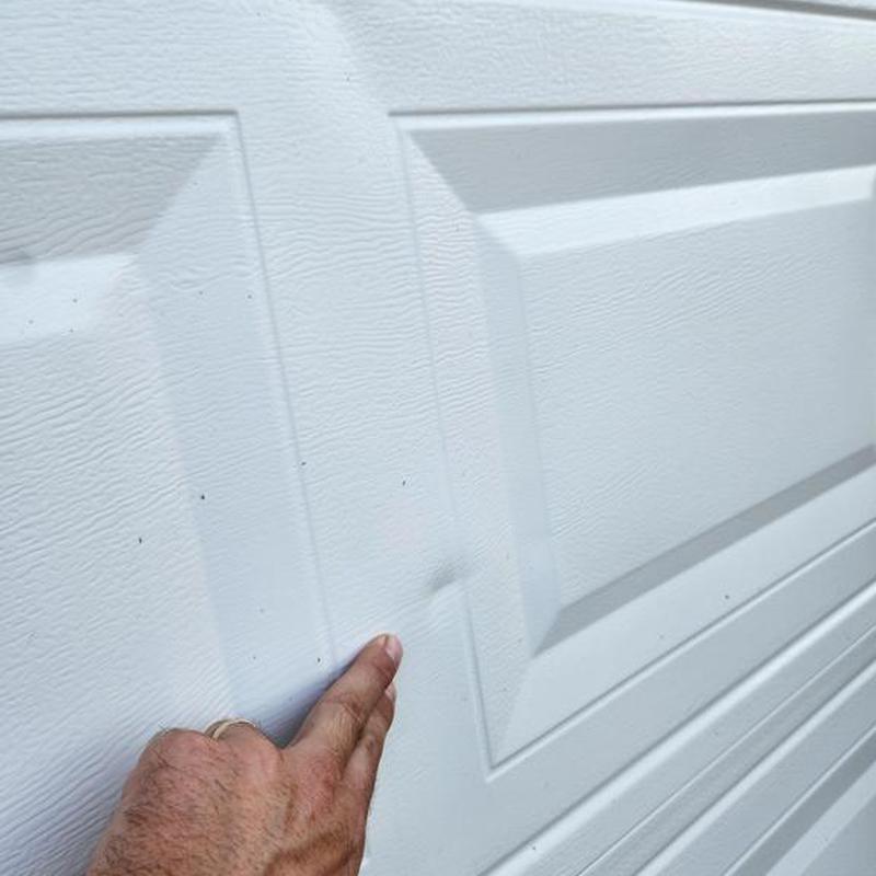 Garage door panel with hail damage dent close-up