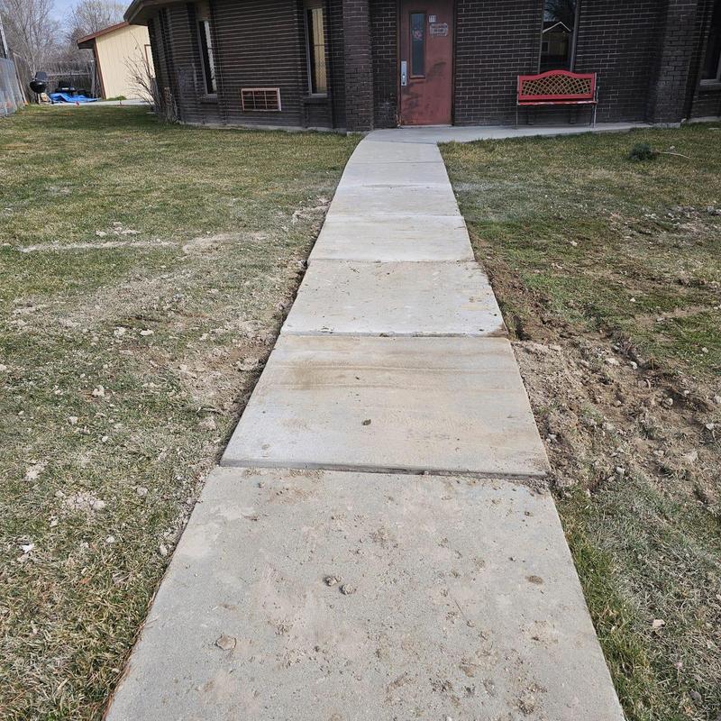 Concrete sidewalk with fresh excavation edges near building entrance