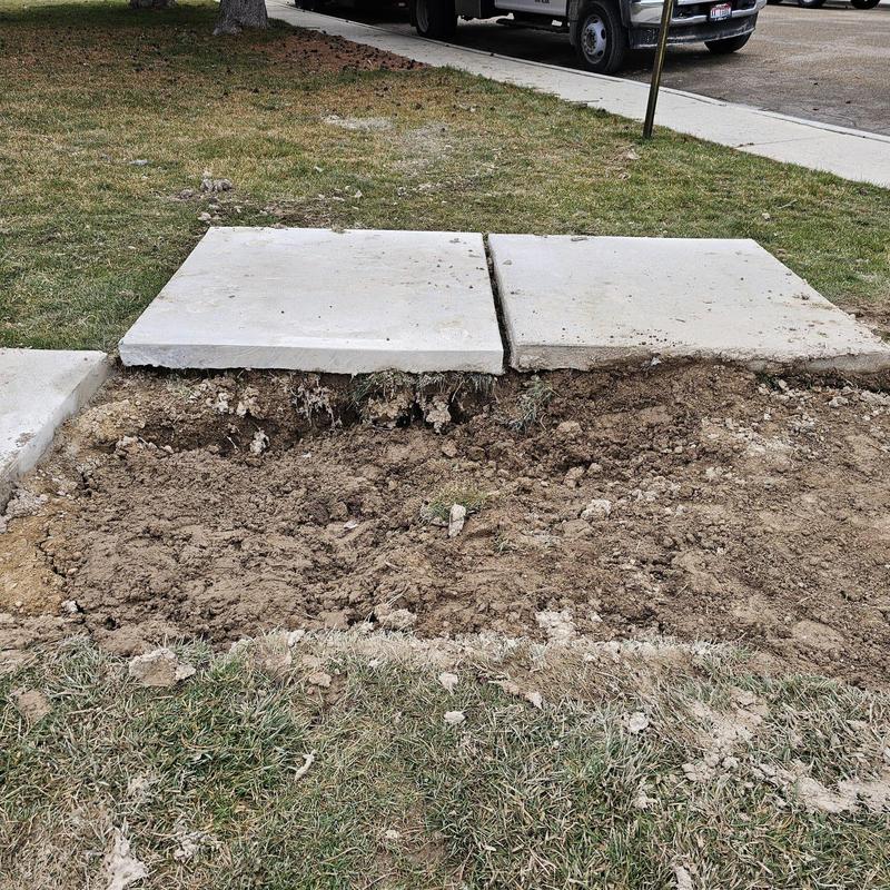 Water service line excavation with removed sidewalk slabs