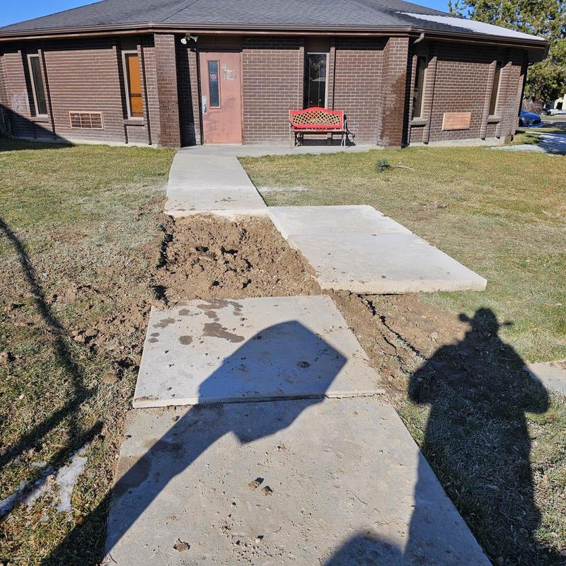 Concrete sidewalk excavation exposing water line repair area