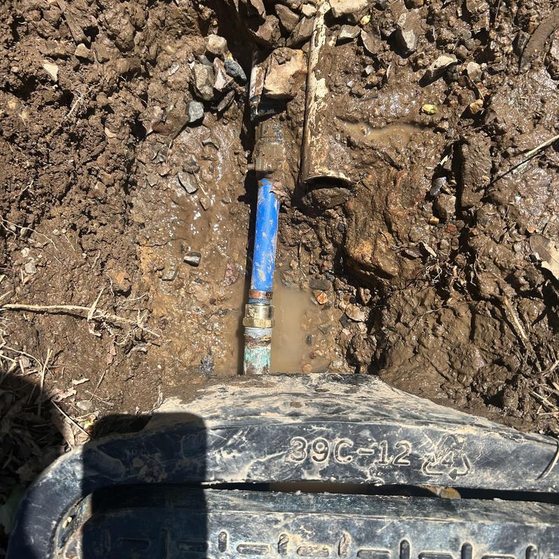 Water service pipe leak at meter in muddy trench Water service pipe leak at meter in muddy trench