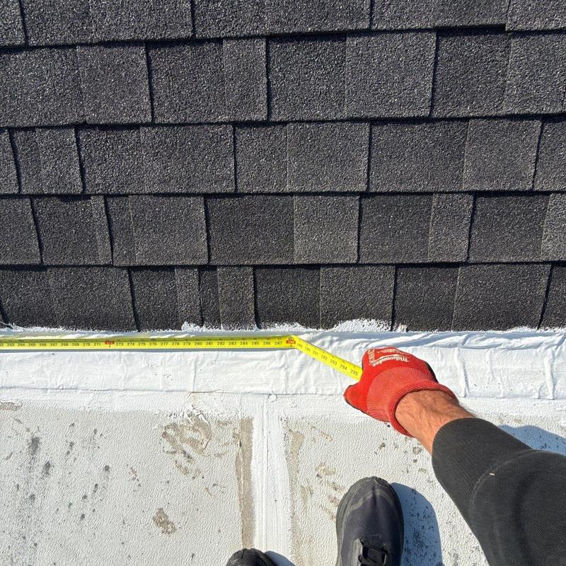 Roof edge with measuring tape during leak inspection