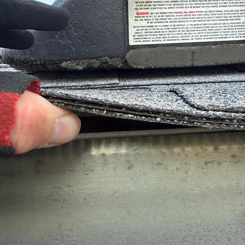 Roof shingles lifted to inspect underlying metal flashing
