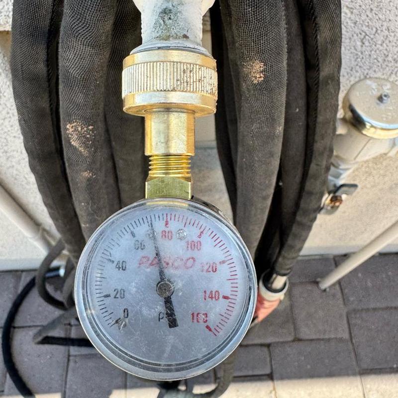 Water pressure gauge showing 80 psi on copper pipe connection