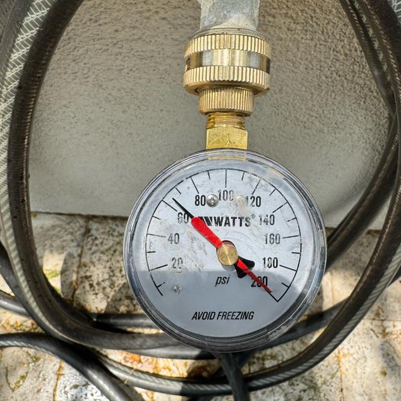 Water pressure gauge showing 80 psi reading outdoors