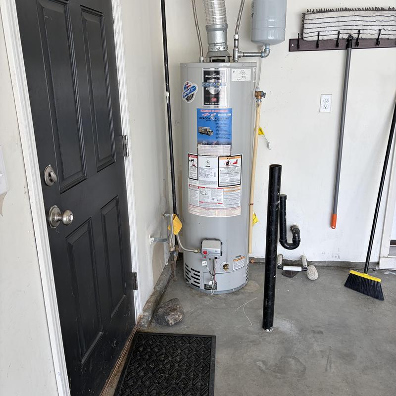 Water heater and vent pipe near garage door and tools