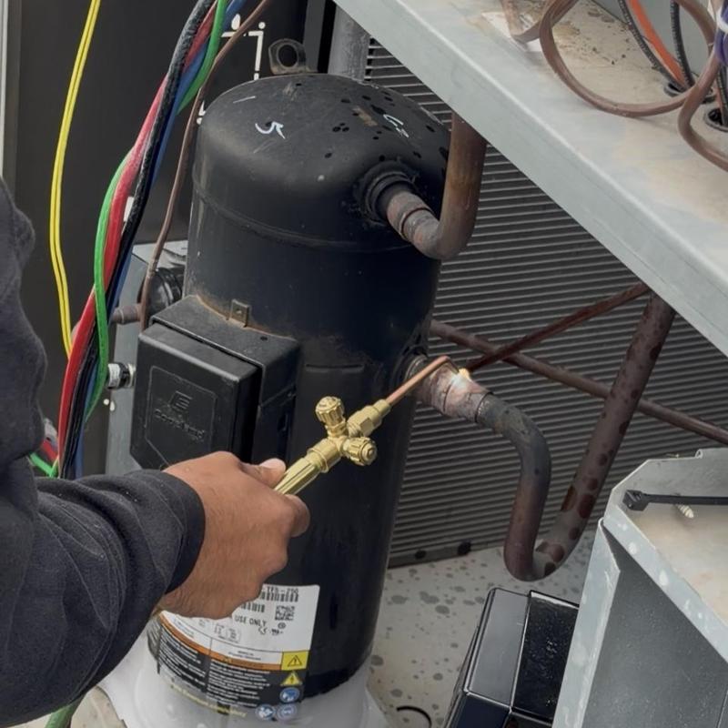 HVAC compressor with welding torch on commercial unit