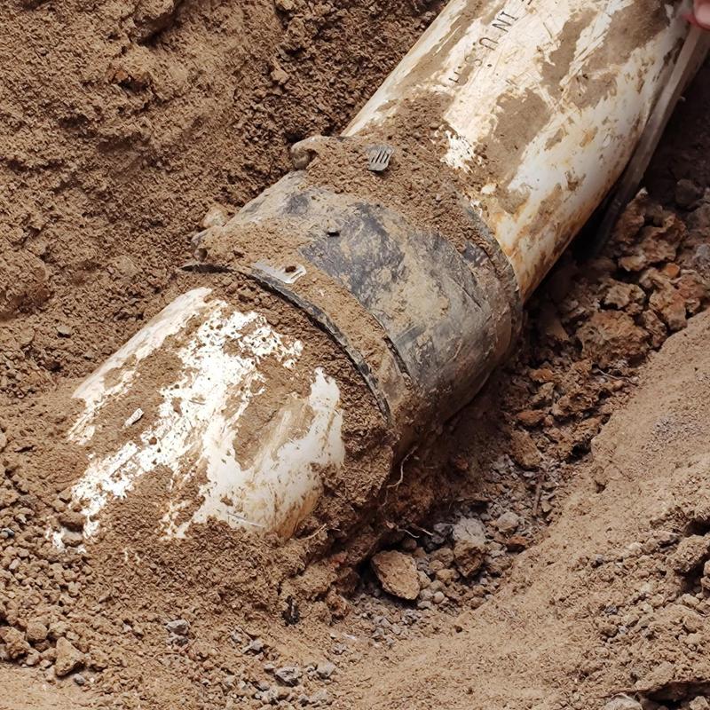 Sewer pipe joint with coupling buried in dirt Sewer pipe joint with coupling buried in dirt