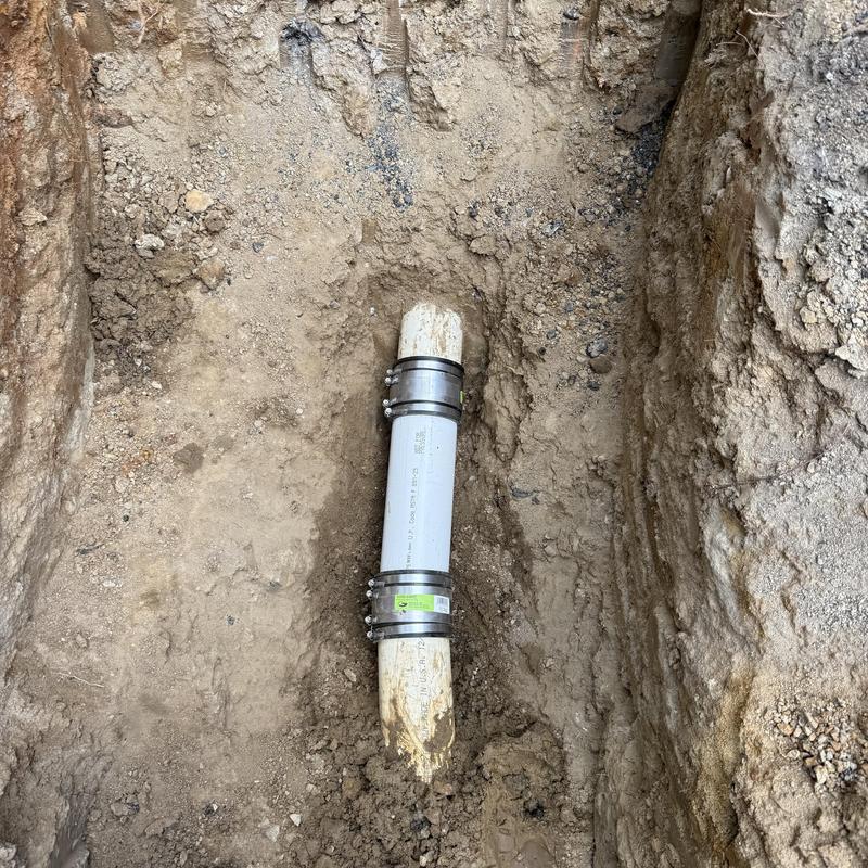 Sewer line coupling with stainless steel bands in trench Sewer line coupling with stainless steel bands in trench