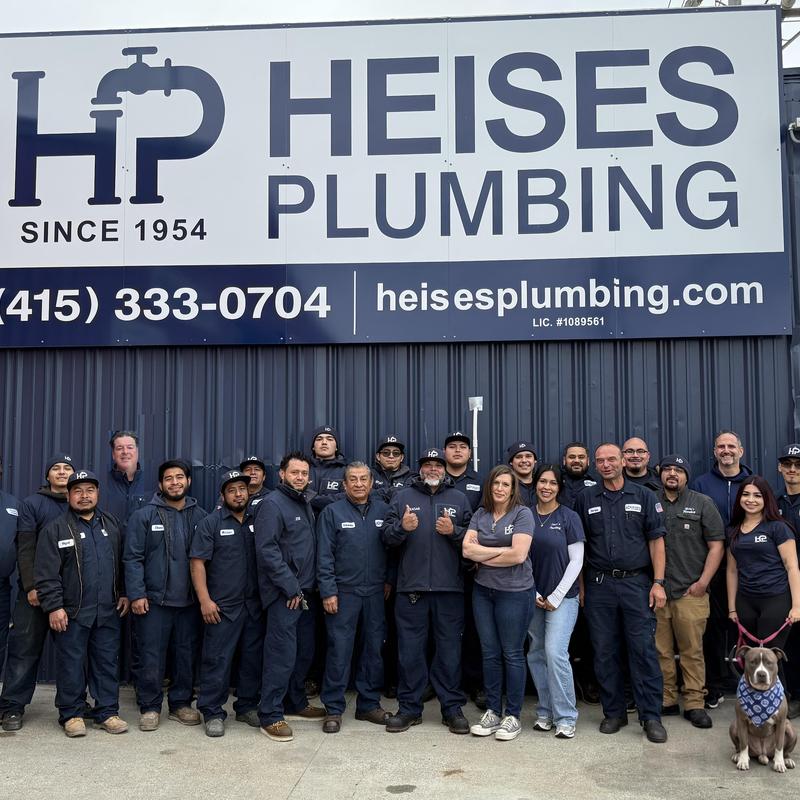 Plumbing service team standing under company sign Plumbing service team standing under company sign