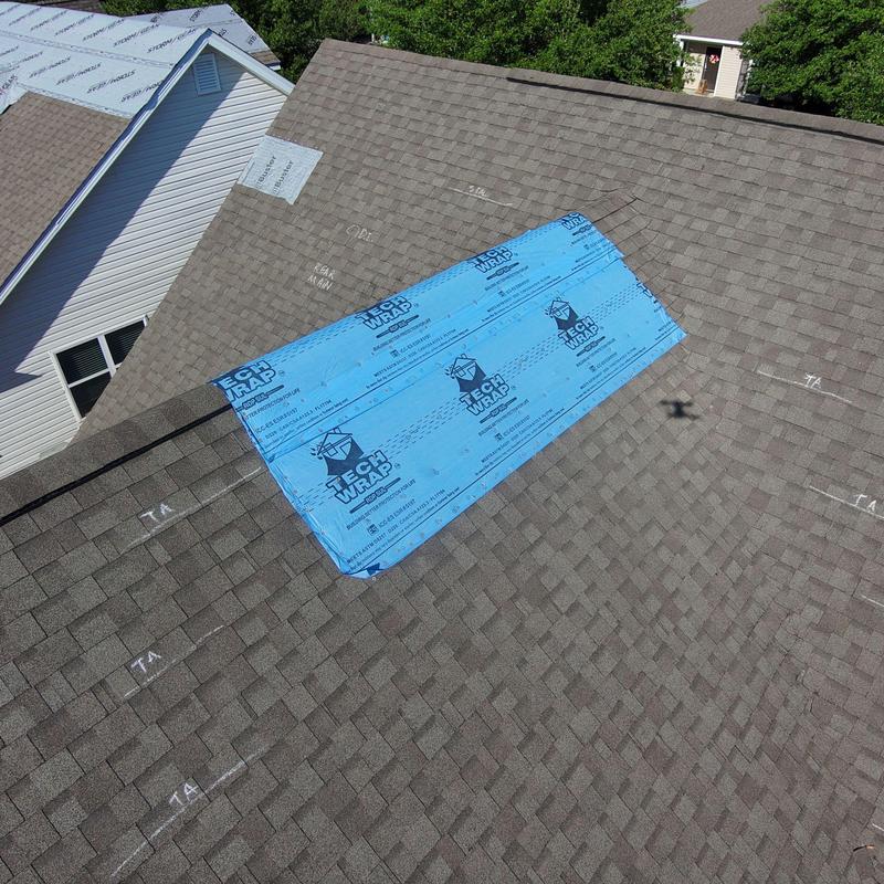 Roof shingles with blue tech wrap patch after wind damage Roof shingles with blue tech wrap patch after wind damage