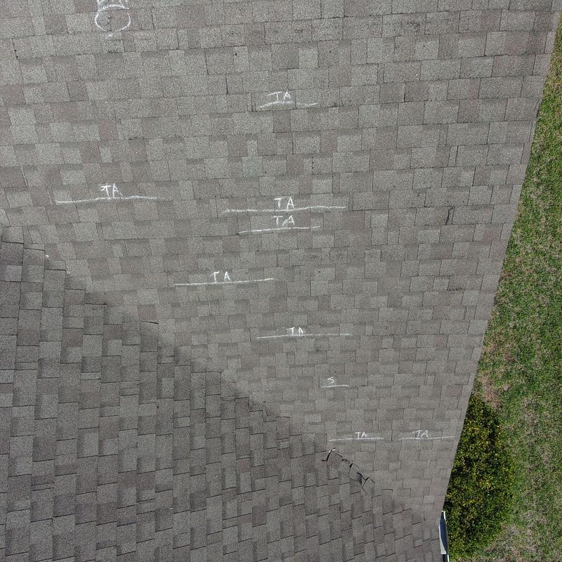 Asphalt roof shingles with marked wind damage Asphalt roof shingles with marked wind damage