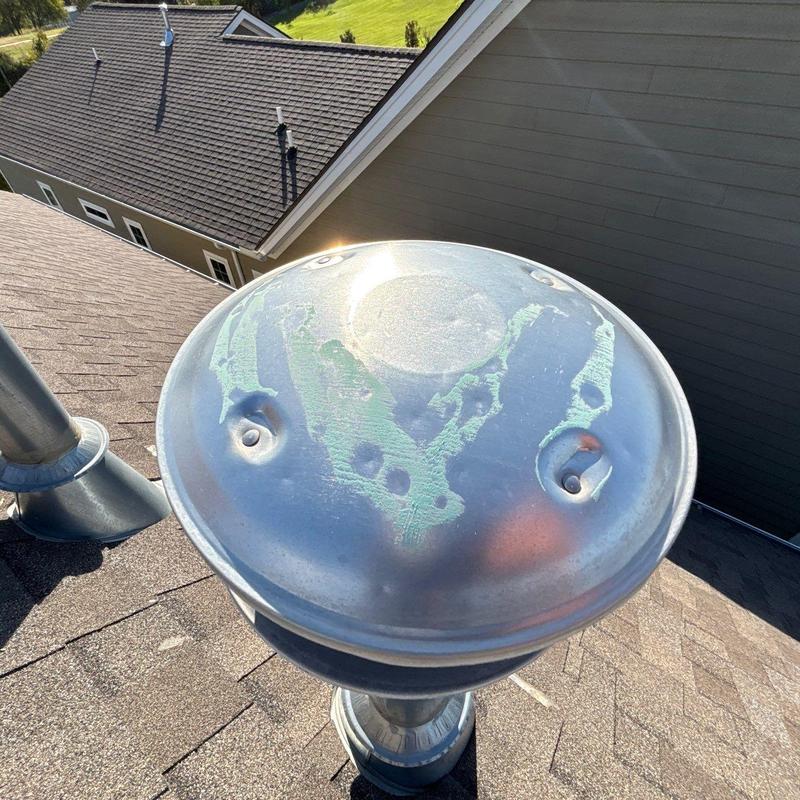 Metal vent cap with hail damage on asphalt roof