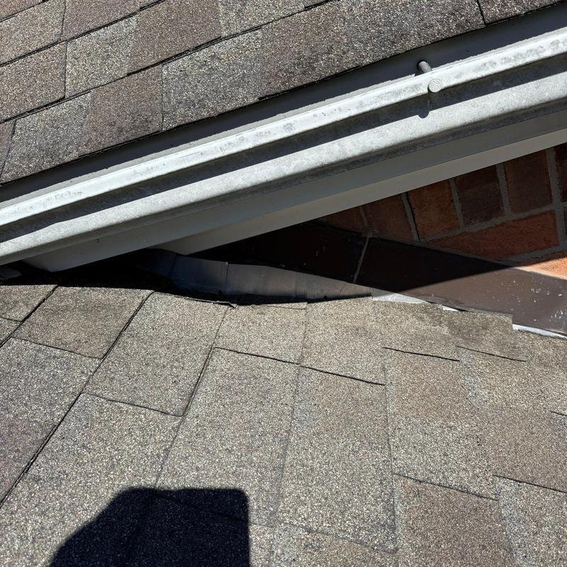 Roof shingles with hail damage near flashing and gutter