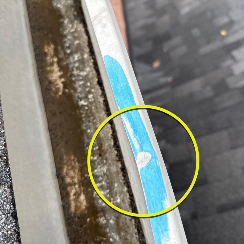Metal roof edge with hail impact damage marked in blue