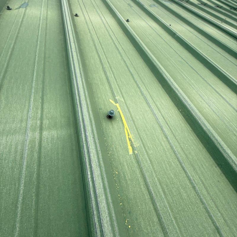 Metal roof panel with hail damage and fasteners