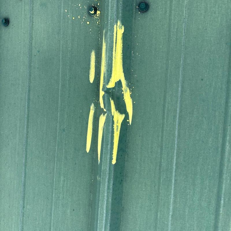 Metal roof hail damage with yellow marking