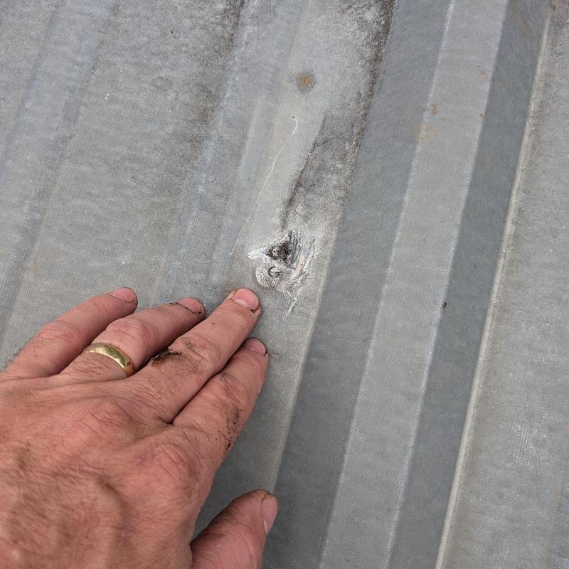 Metal roof panel close-up with damaged screw hole Metal roof panel close-up with damaged screw hole