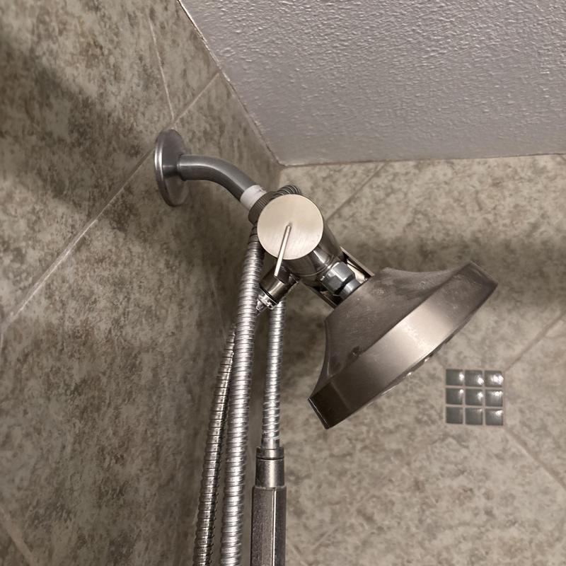 Metal showerhead with handheld hose on tiled wall Metal showerhead with handheld hose on tiled wall