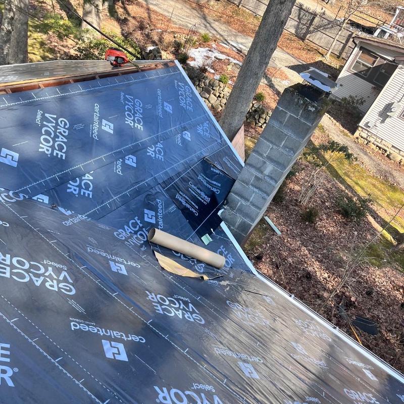 Roof underlayment installation near chimney on residential roof Roof underlayment installation near chimney on residential roof