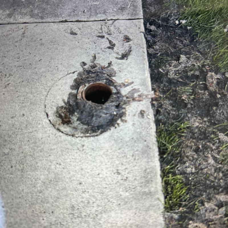 Mainline sewer access in concrete driveway with soil nearby