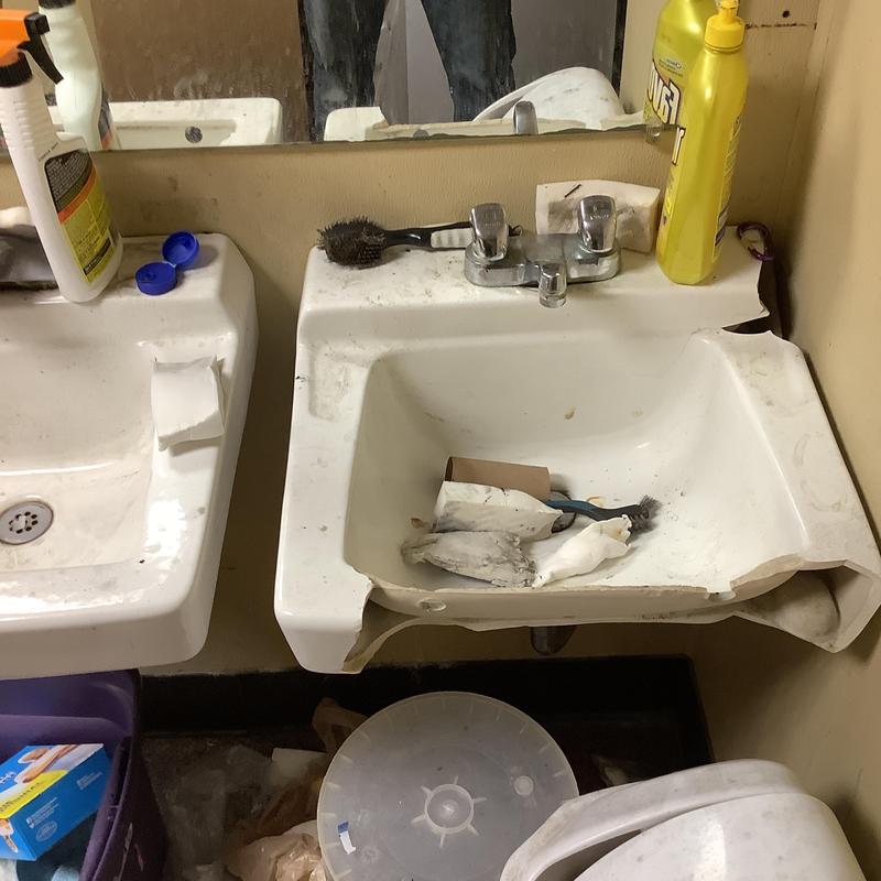 Wall hung sink with damaged basin and clutter Wall hung sink with damaged basin and clutter