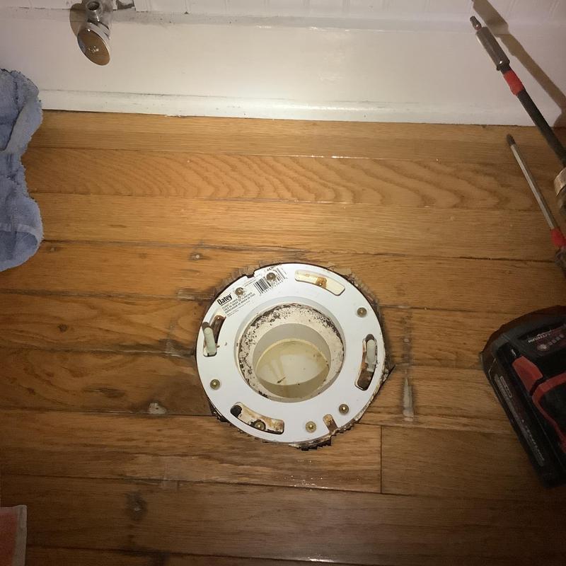 Toilet flange on hardwood floor with nearby tools Toilet flange on hardwood floor with nearby tools