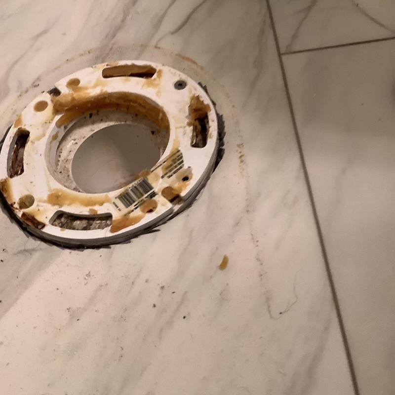 Toilet flange on marble tile floor with rust stains Toilet flange on marble tile floor with rust stains