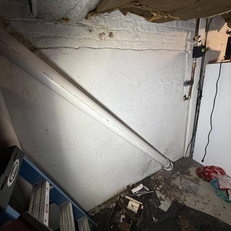 Basement PVC drain line angled against wall in home Basement PVC drain line angled against wall in home