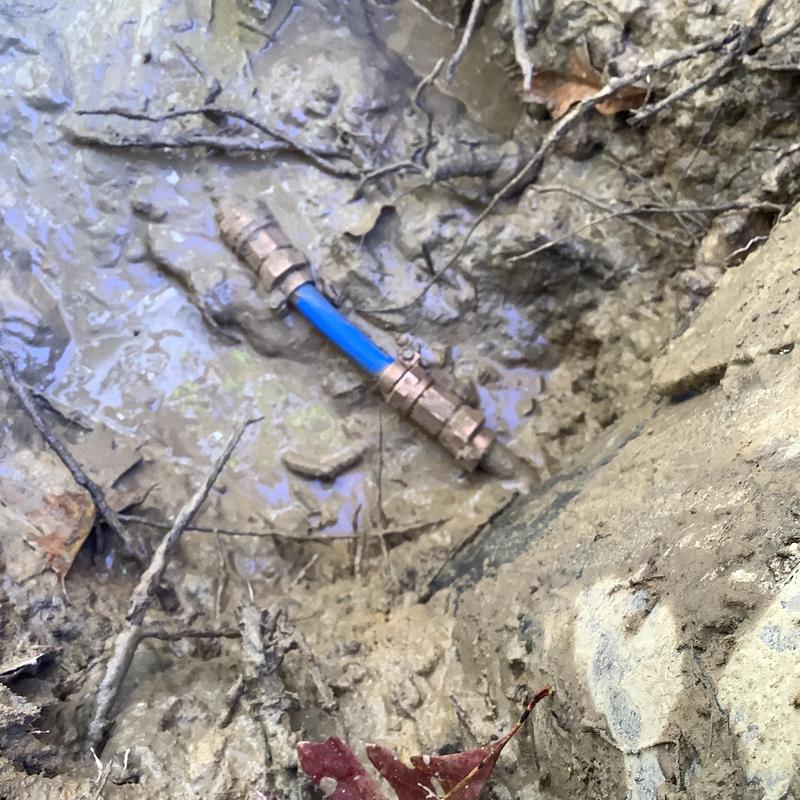 Blue main waterline pipe with brass fittings in muddy soil Blue main waterline pipe with brass fittings in muddy soil