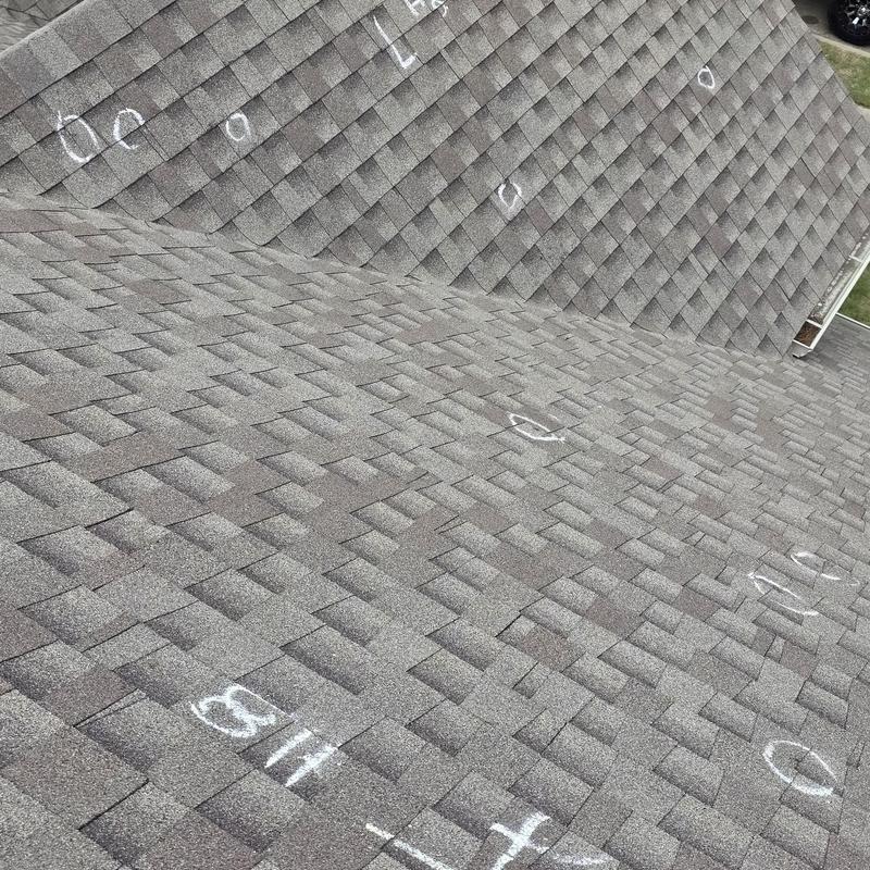 Asphalt roof shingles with hail damage marked in chalk