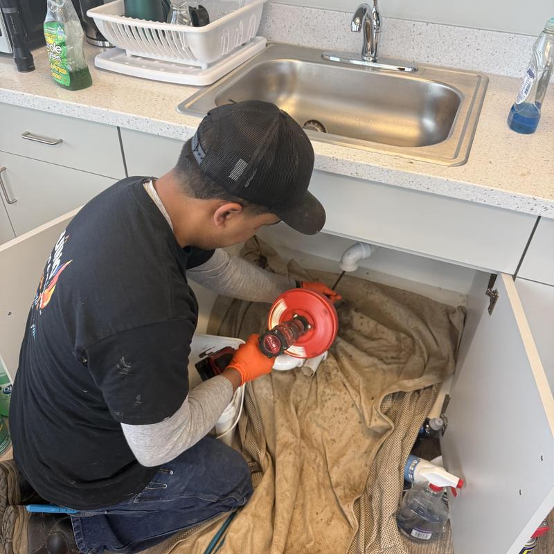 Kitchen sink drain cleaning with auger tool in cabinet Kitchen sink drain cleaning with auger tool in cabinet