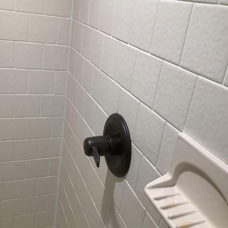 Delta bronze shower faucet handle on white tile wall Delta bronze shower faucet handle on white tile wall