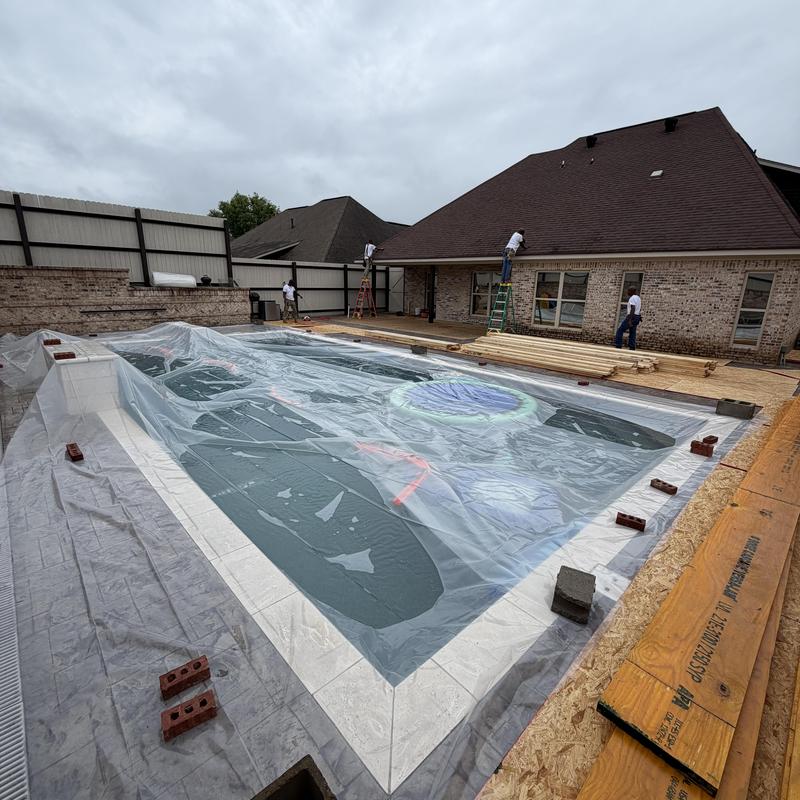 Covered swimming pool framing near brick house