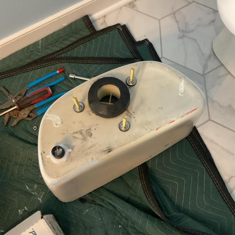Toilet tank with mounting bolts and gasket on mat Toilet tank with mounting bolts and gasket on mat
